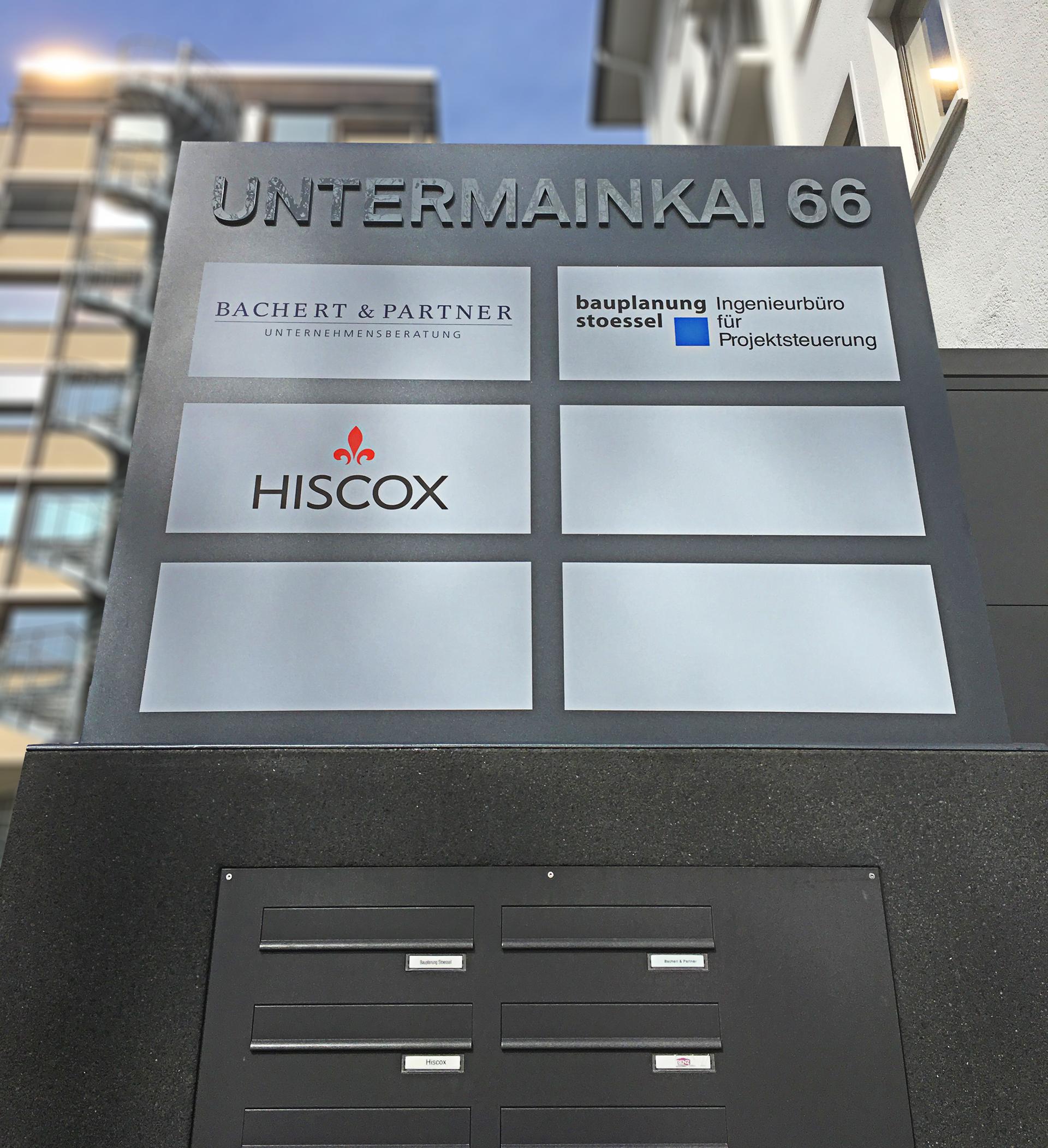 Stele mit aufgesetzten Acryl Fräsbuchstaben und Firmaschilder in Form von Folienaufkleber Werbespot in Frankfurt Umgebung von anplakt